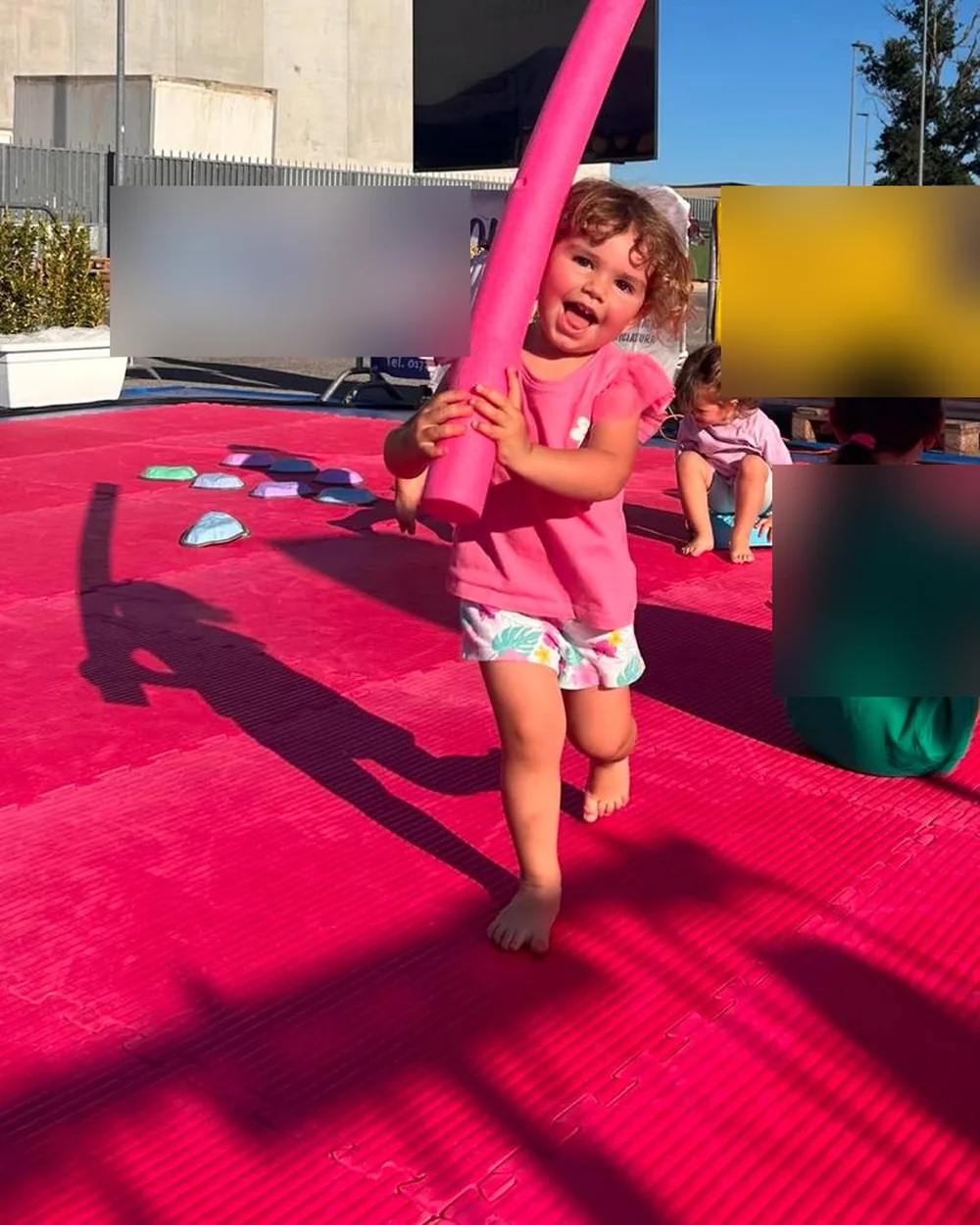 Bambina sorridente con un tubo di gommapiuma rosa durante Crescere in Movimento