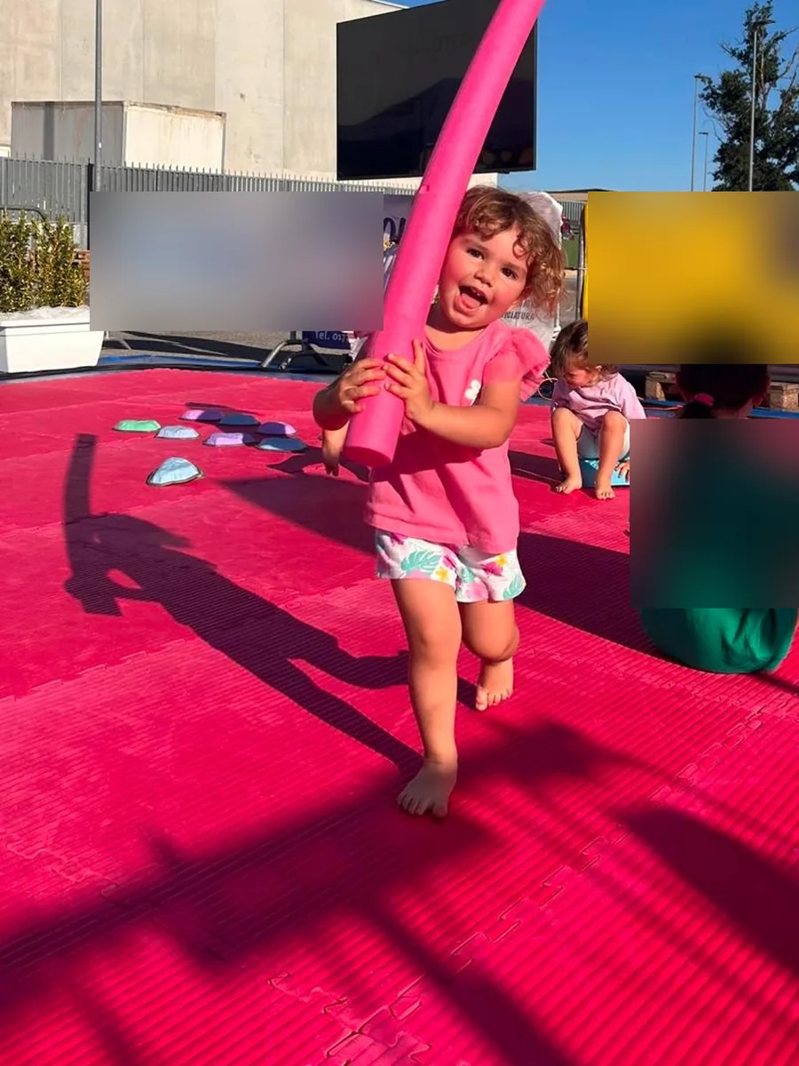 Bambina sorridente con un tubo di gommapiuma rosa durante Crescere in Movimento